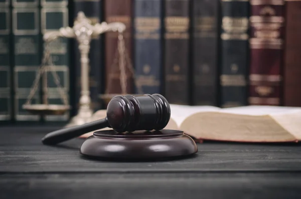 Richtergabel, Gesetzesbücher und Justizwaagen auf schwarzem Holzgrund. — Stockfoto