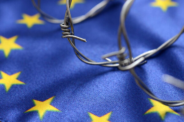 Флаг Европейского Союза и колючая проволока, миграция в Европейский союз
