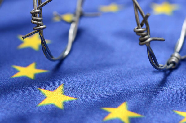 Флаг Европейского Союза и колючая проволока, миграция в Европейский союз
