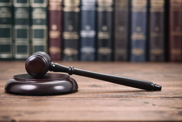 Soudce kladívkem na černém pozadí dřevěná před právnické knihovny — Stock fotografie