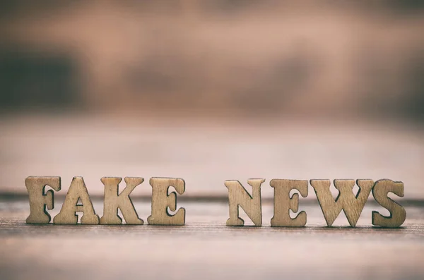 Fake news wooden letters on a wooden background. Fake news as a form of news consisting of deliberate disinformation or hoaxes spread via traditional news media (print and broadcast)