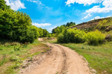 Toprak yol yeşil ağaçlar, kayalar karşı 