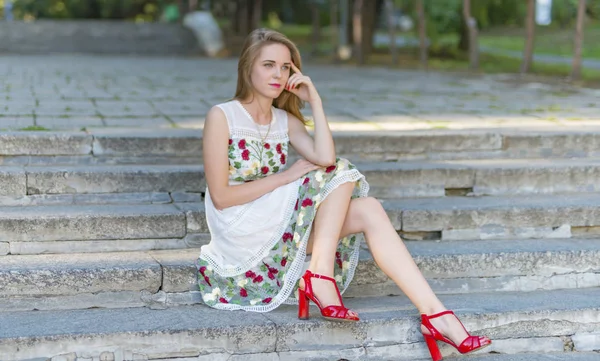 Beautiful girl sitting on stone steps — Stock Photo, Image