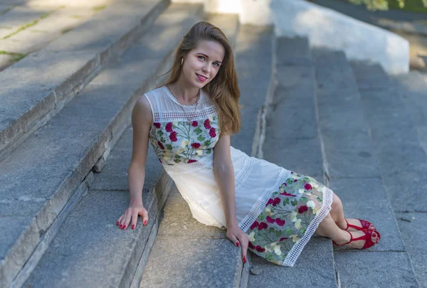 Menina bonita sentada em degraus de pedra — Fotografia de Stock