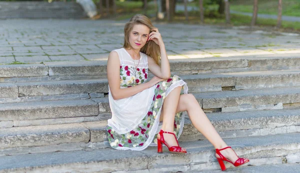 Beautiful girl sitting on stone steps — Stock Photo, Image