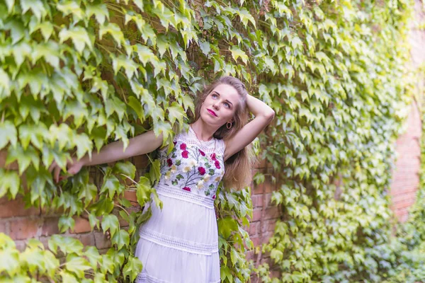 Chica en el fondo de una pared con follaje verde —  Fotos de Stock