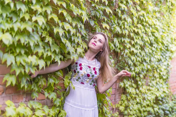 Chica en el fondo de una pared con follaje verde — Foto de Stock