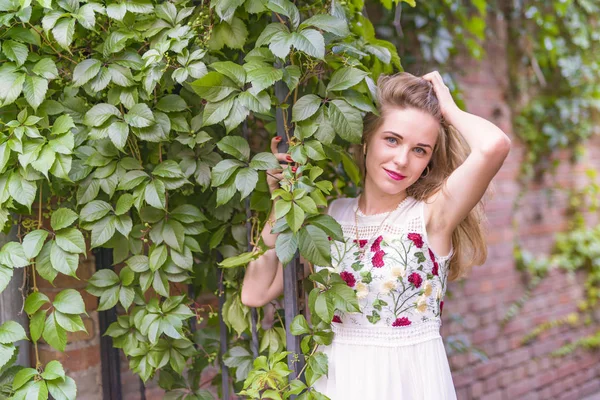 Meisje op de achtergrond van een muur met groen blad — Stockfoto