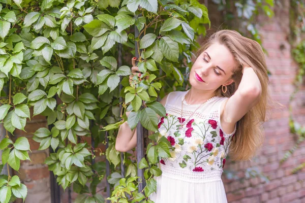 Flicka på bakgrunden av en vägg med grönt bladverk — Stockfoto