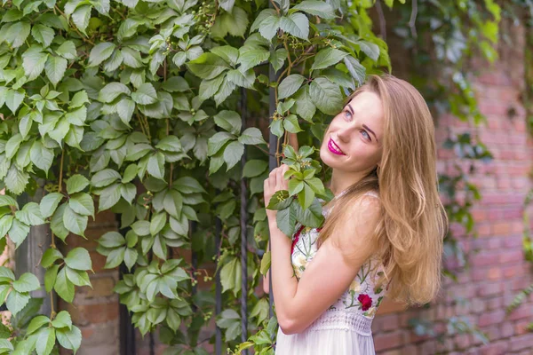 Chica en el fondo de una pared con follaje verde — Foto de Stock