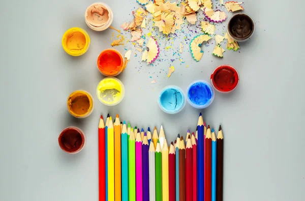 Buntstifte und Gläser mit Farbe auf grauem Grund — Stockfoto