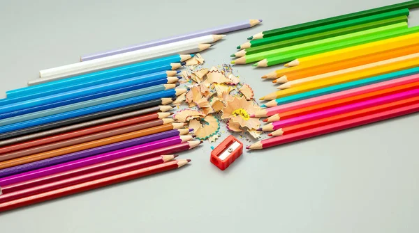 Crayons multicolores avec affûtage et jetons sur un fond gris — Photo