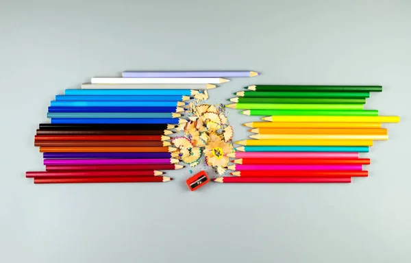 Πολύχρωμα μολύβια με ακόνισμα και πατατάκια σε γκρι φόντο — Φωτογραφία Αρχείου