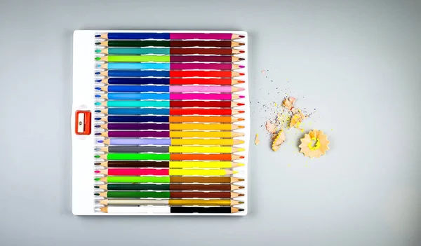 Wielokolorowe ołówki z temperówką w pudełku na szarym tle — Zdjęcie stockowe
