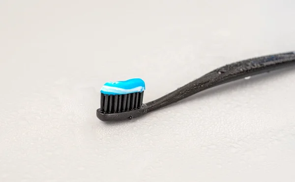 Black Toothbrush Blue Toothpaste Gray Background — Stock Photo, Image