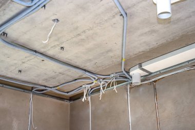 Beton tavandaki kıvrımlarda plastik bağlantı kutuları ve kablo var.