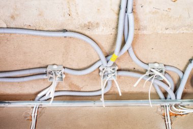 Beton tavandaki kıvrımlarda plastik bağlantı kutuları ve kablo var.