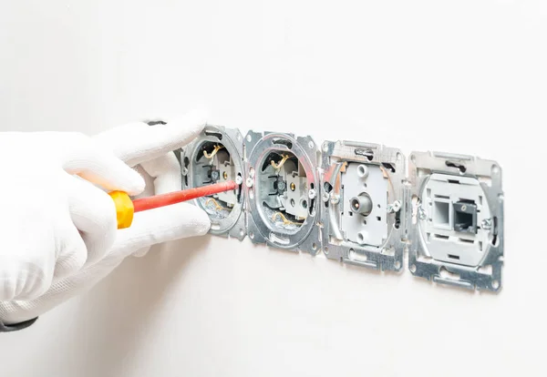 The process of installing internal sockets for power, internet and television on a white plaster wall background