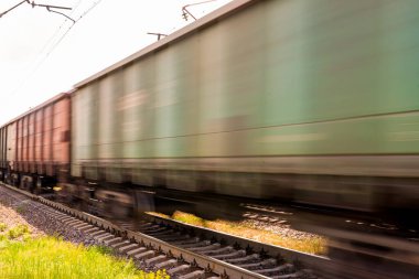 Yaz mevsiminde elektrikli demiryolunda yük vagonlarıyla hareket eden tren.