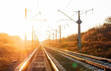 Sonbaharda günbatımı arka planında elektrikli demiryolu