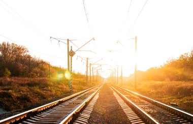 Sonbaharda günbatımı arka planında elektrikli demiryolu