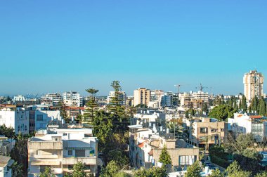 Yazın gökyüzünün arka planında özel evleri ve yüksek binaları olan şehir.
