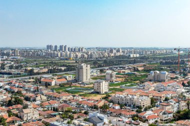 Yazın gökyüzünün arka planında özel evleri ve yüksek binaları olan şehir.