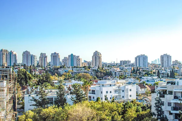 Yazın gökyüzünün arka planında özel evleri ve yüksek binaları olan şehir.