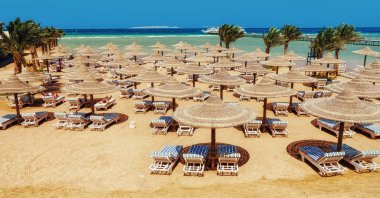 Chaise lounge and parasols on the beach against the blue sky and sea. Egypt, Hurghada clipart