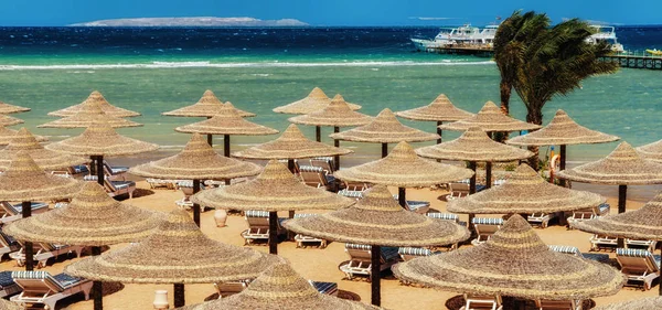 Utazókocsi Lebzsel és napernyők a strandon a kék ég ellen és a — Stock Fotó
