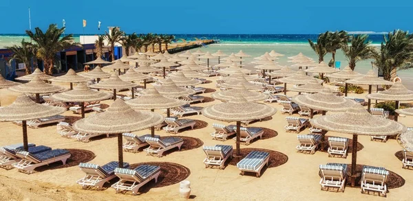 Chaise lounge en parasols op het strand tegen de blauwe hemel en — Stockfoto