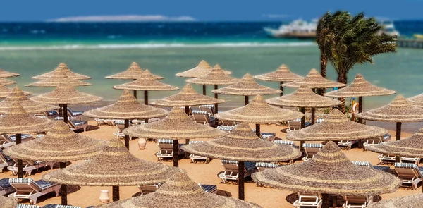 Σαλόνι μονίππων και ομπρέλες στην παραλία κατά το γαλάζιο του ουρανού και — Φωτογραφία Αρχείου