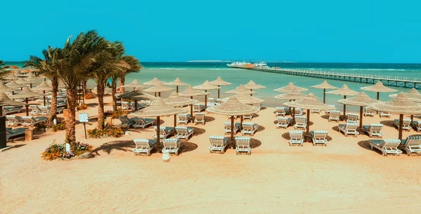 Chaise lounge e guarda-sóis na praia contra o céu azul e — Fotografia de Stock