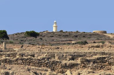 Dağlar ve Antik kalıntıların arkeolojik Park Pafos, Kıbrıs için arka plan üzerinde beyaz deniz feneri.