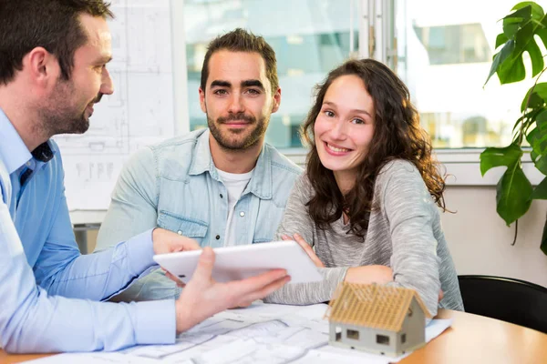 Young attractive couple signing contract with real estate agent — Stock Photo, Image