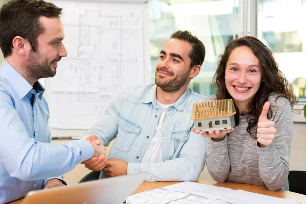 Young attractive couple signing contract with real estate agent — Stock Photo, Image