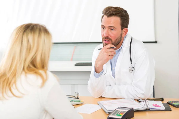 Joven médico atractivo escuchando a su paciente —  Fotos de Stock