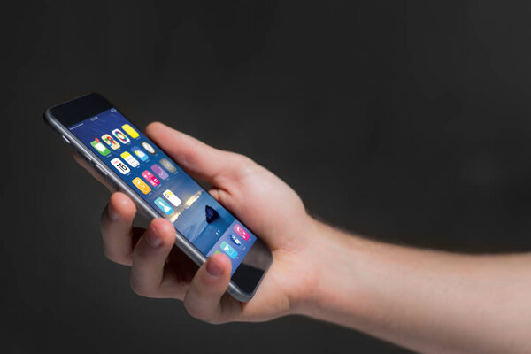 Hand holding black smartphone with operating system screen