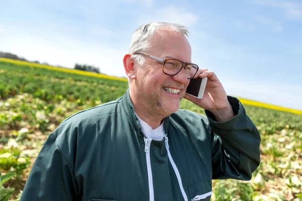 Senior attractive farmer calling in a field with smartphone- Nat — Stock Photo, Image