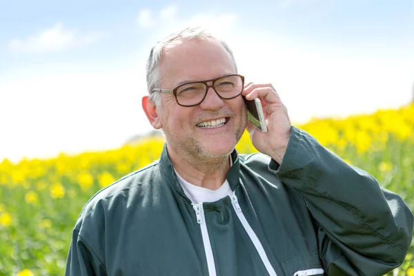 Senior attraente agricoltore chiamando in un campo con smartphone-Nat — Foto Stock