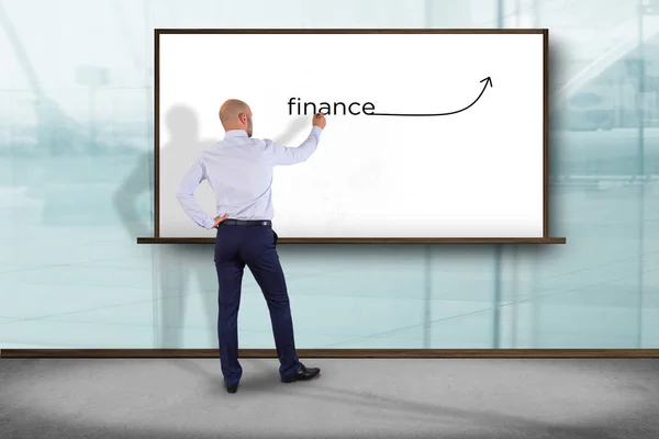 Üzletember egy fal, a szó pénzügyi írás előtt — Stock Fotó