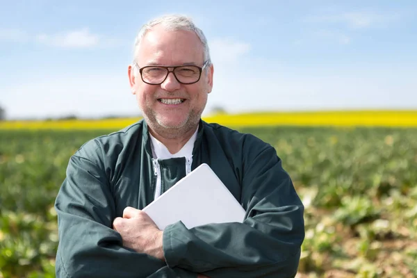 Senior attraente agricoltore che lavora in un campo aiutato dal suo tablet — Foto Stock