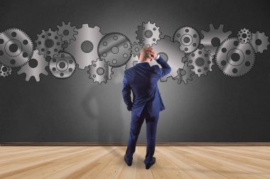 İşadamı bir cog wheel arabirimde yazma bir duvar önünde 