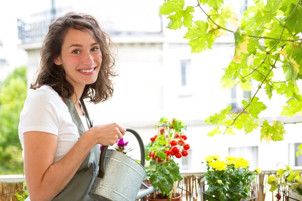 Giovane donna che innaffia pomodori sul suo giardino balcone della città — Foto Stock