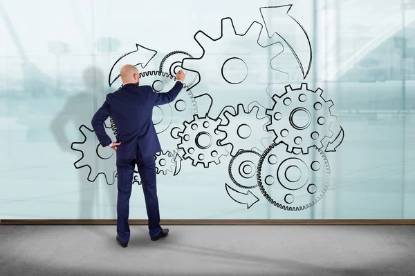 İşadamı bir cog wheel arabirimde yazma bir duvar önünde 