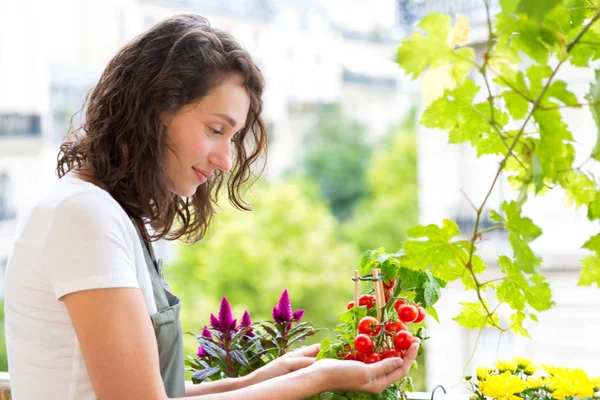 Jonge vrouw met het verzorgen van haar planten en groenten op haar stad — Stockfoto