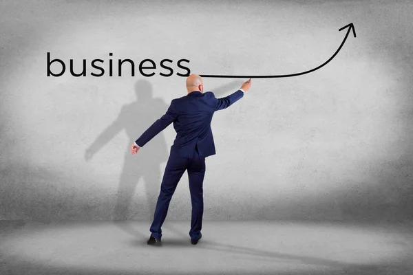 Businessman in front of a wall writing the word business with a — Stock Photo, Image