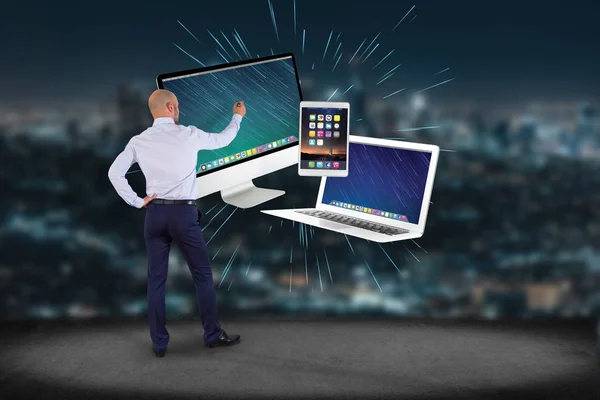 Empresario frente a una pared con pantalla de ordenador y dispositivos — Foto de Stock