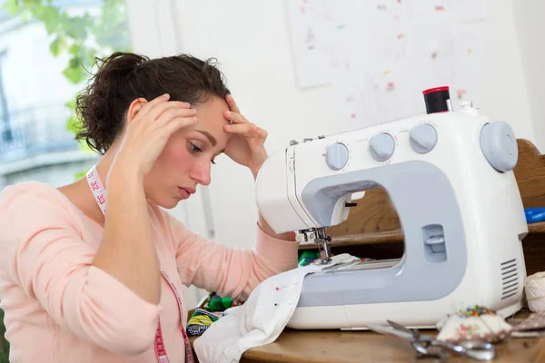 Молода швачка жінка має труднощі з швейною машиною — стокове фото