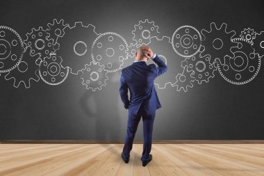 İşadamı bir cog wheel arabirimde yazma bir duvar önünde 